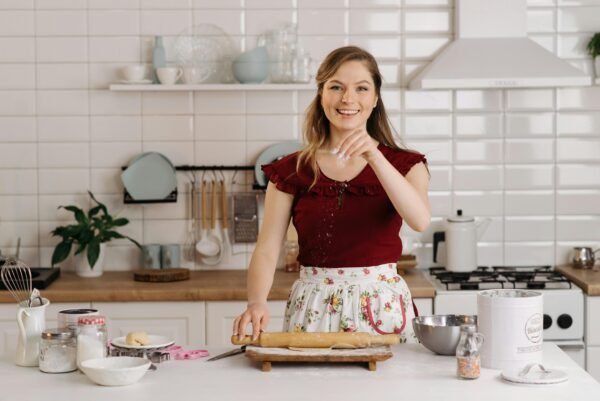 Cheerful woman preparing dough in a bright, modern kitchen setting.